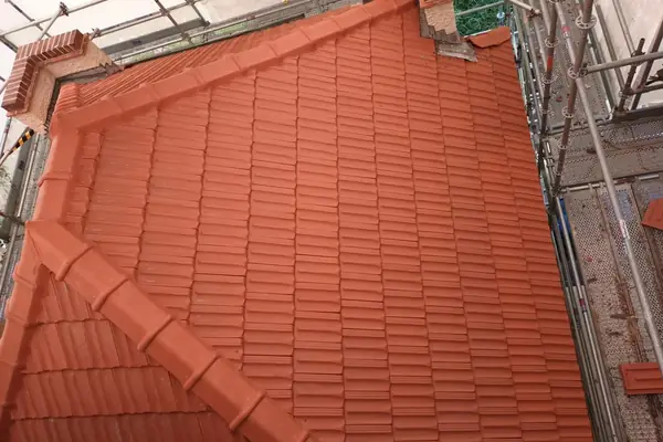 Hipped concrete tile roof painted in terracotta, seen from the scaffold