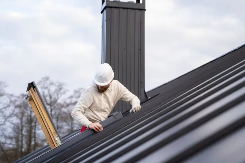 Roofer working on new long-run roofing and flashings around a chimney
